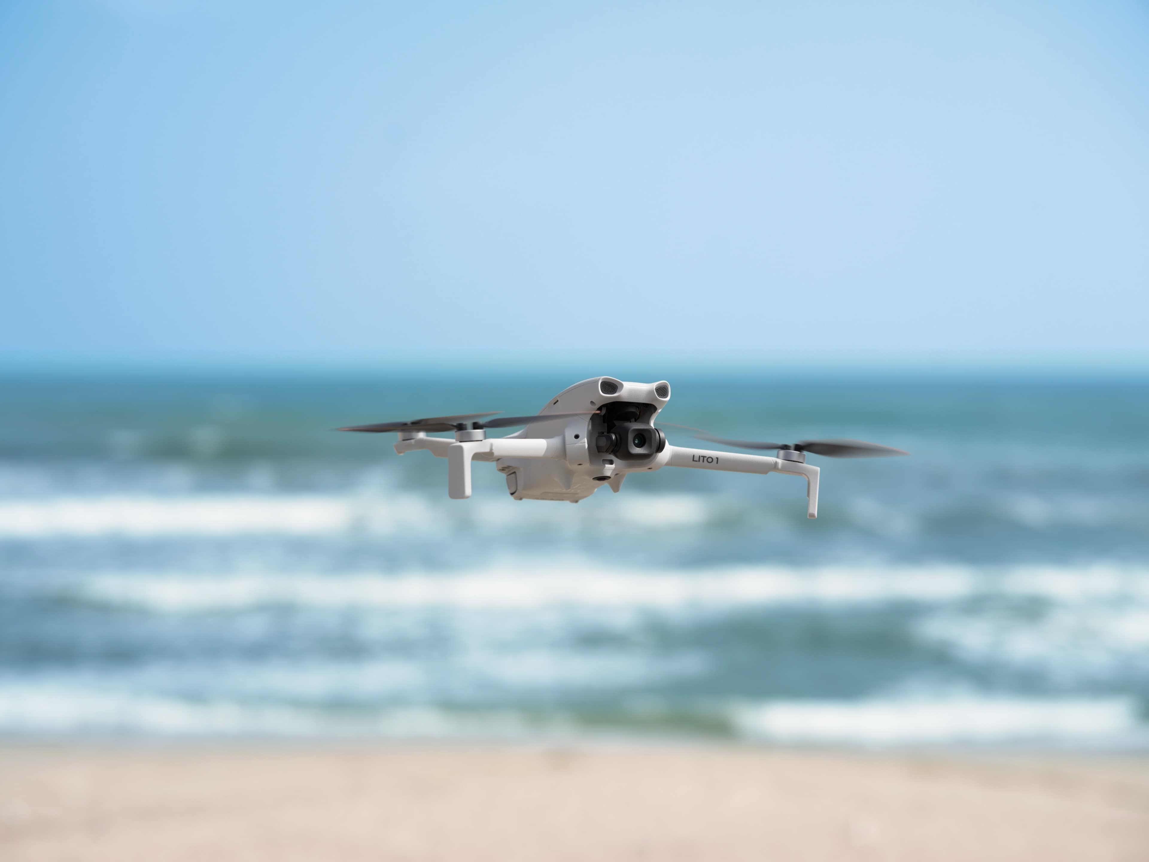 DJI Lito 1 Fly More Combo (DJI RC-N3) Drohne fliegt über den Strand mit Meer im Hintergrund.