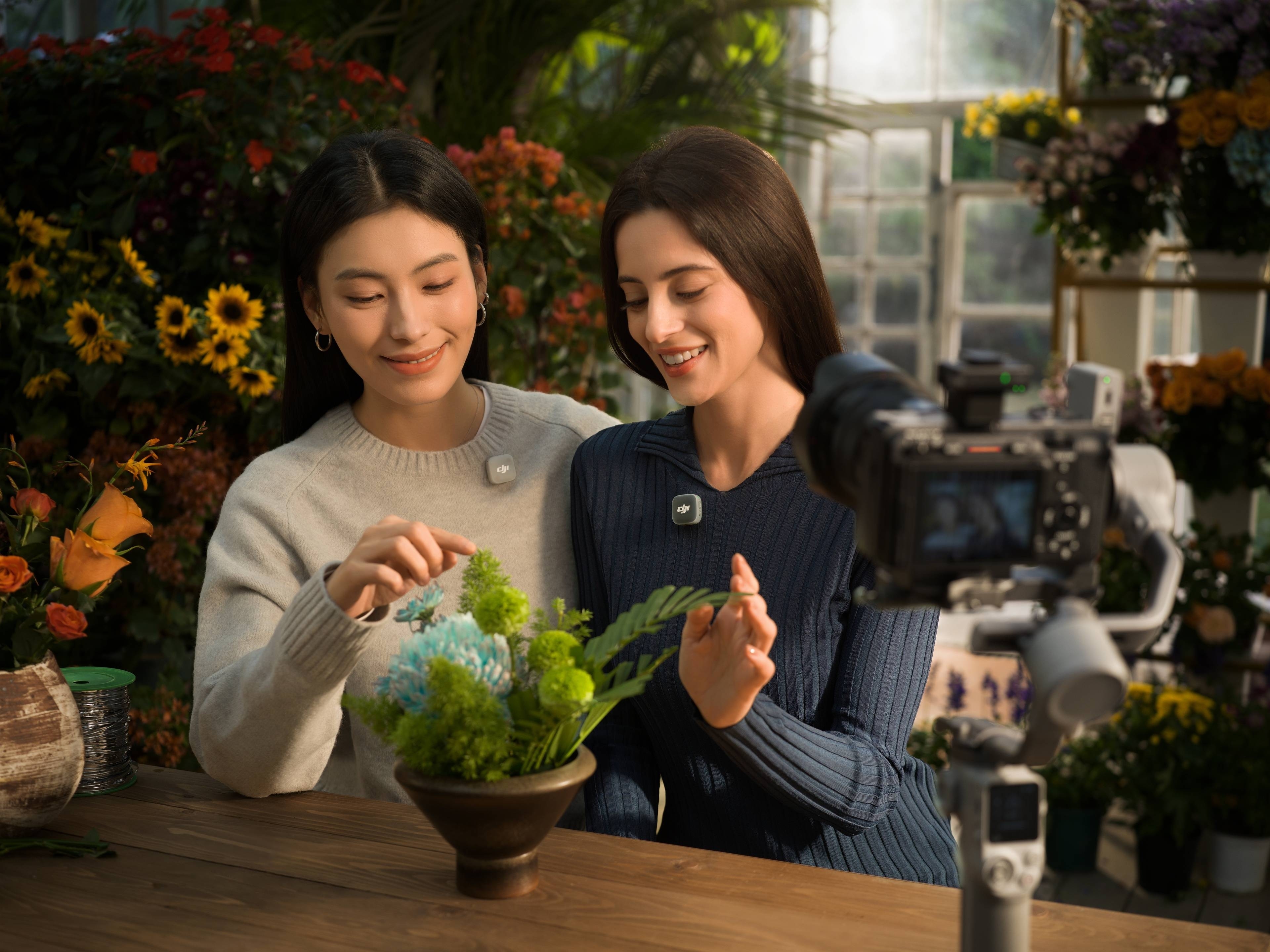 Zwei Frauen in einem Blumenladen, die mit dem DJI Mic Mini 2 (1 TX + 1 RX) kommunizieren und Blumen arrangieren.