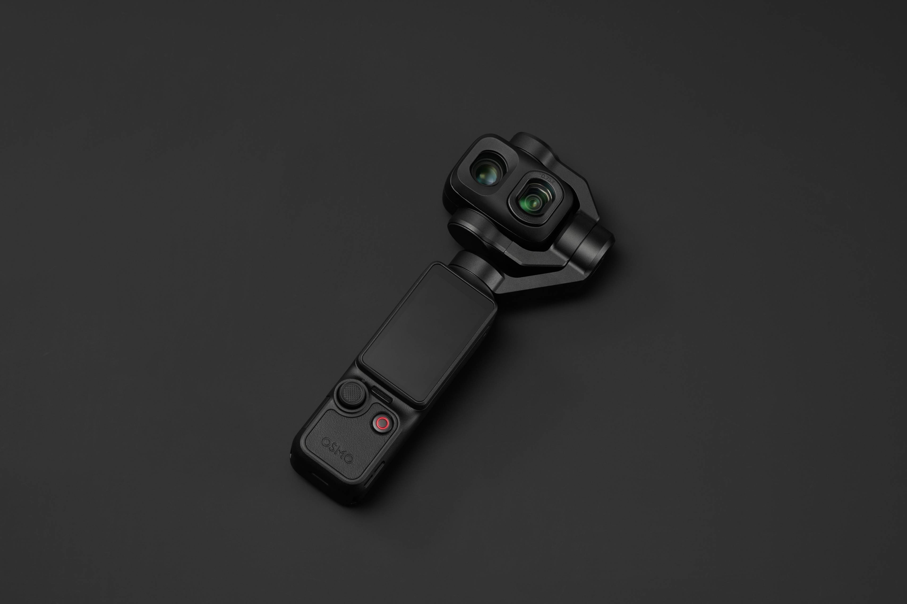 DJI Osmo Pocket 4P Weitwinkelobjektiv: Kompakte Kamera mit zwei Linsen und Steuerungstasten auf schwarzem Hintergrund.