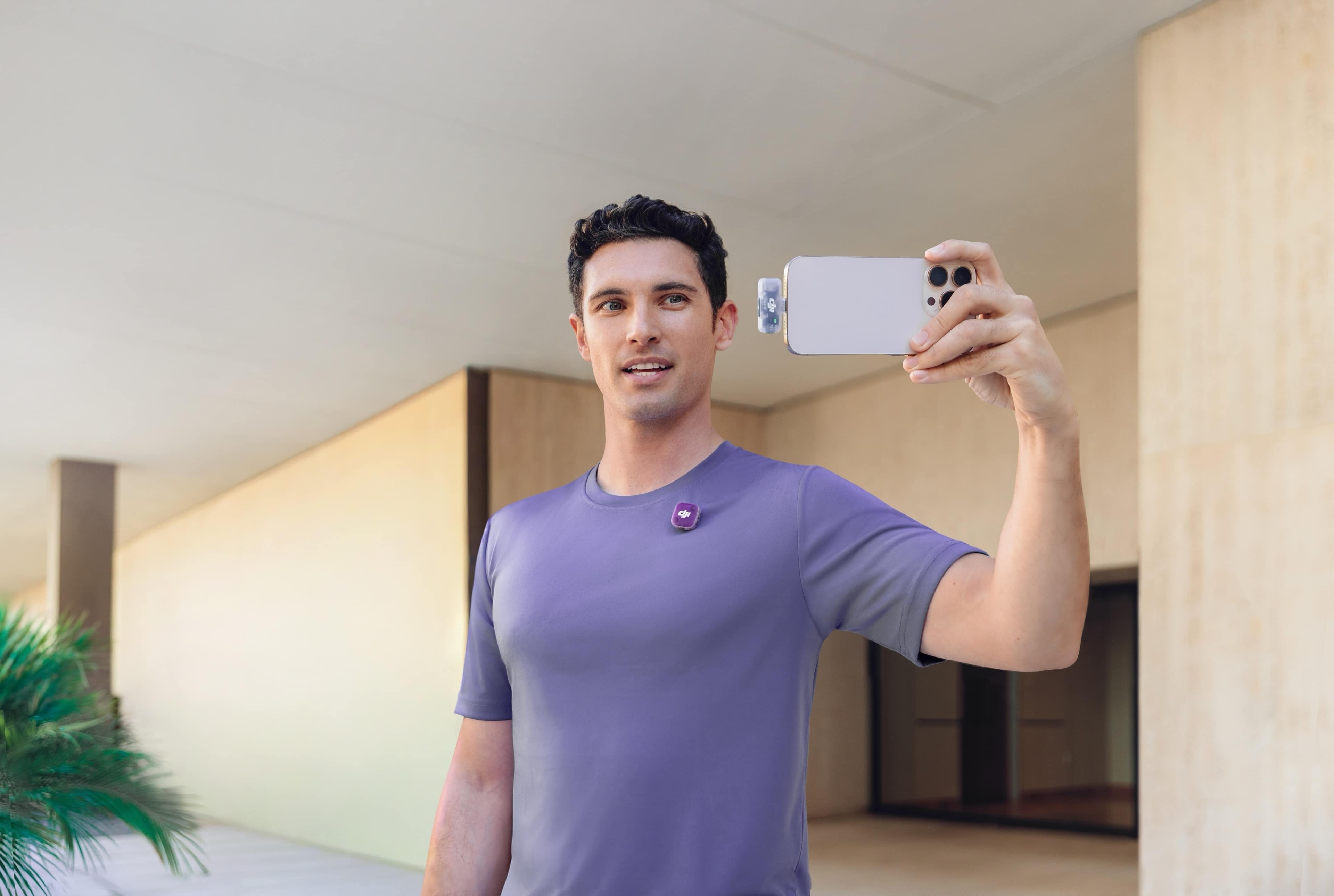 Mann mit DJI Mic Mini 2, 2 TX und 1 RX, hält Smartphone für ein Selfie in moderner Umgebung.