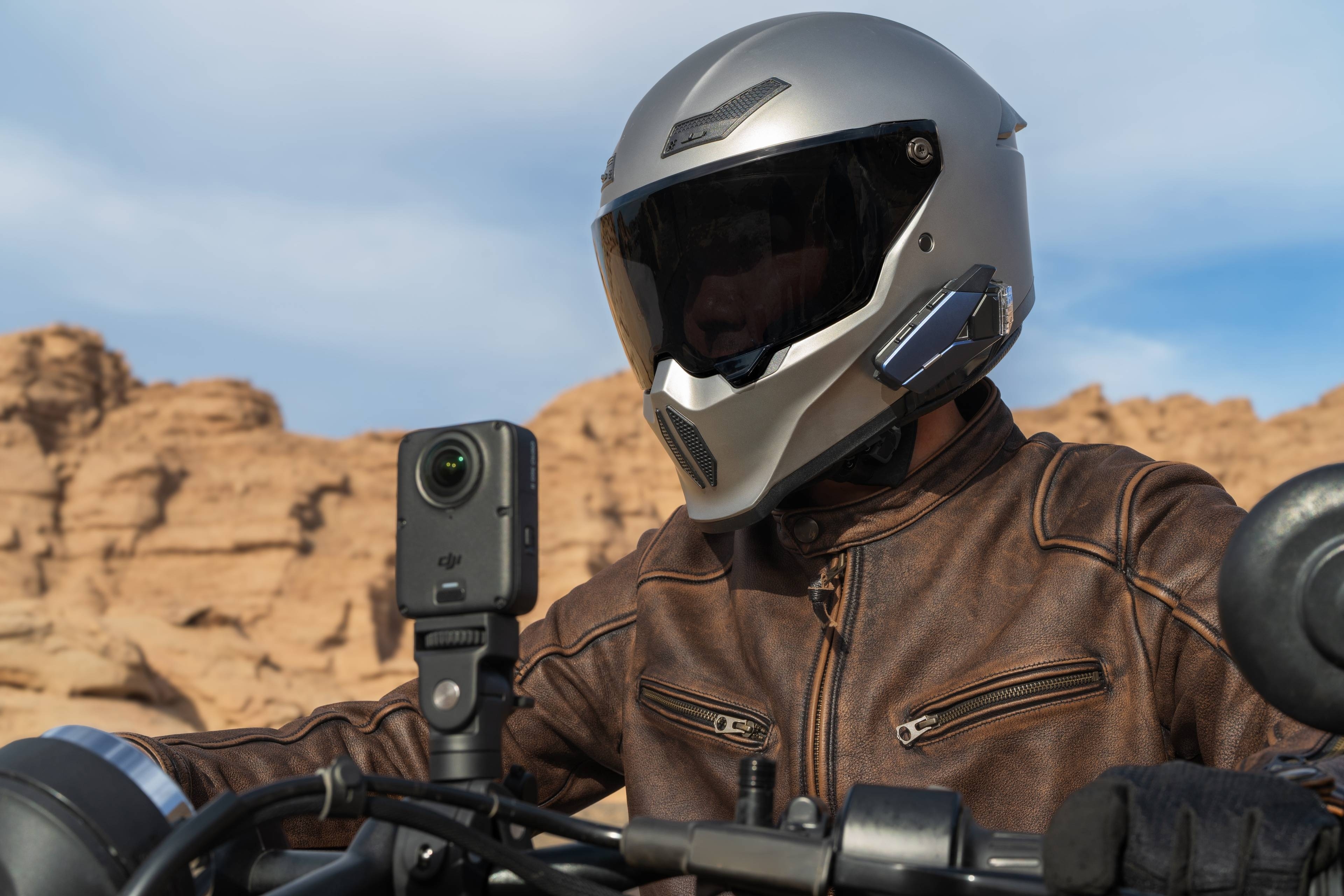DJI Osmo 360 II Kamera montiert auf dem Motorradhelm eines Fahrers in einer felsigen Landschaft.