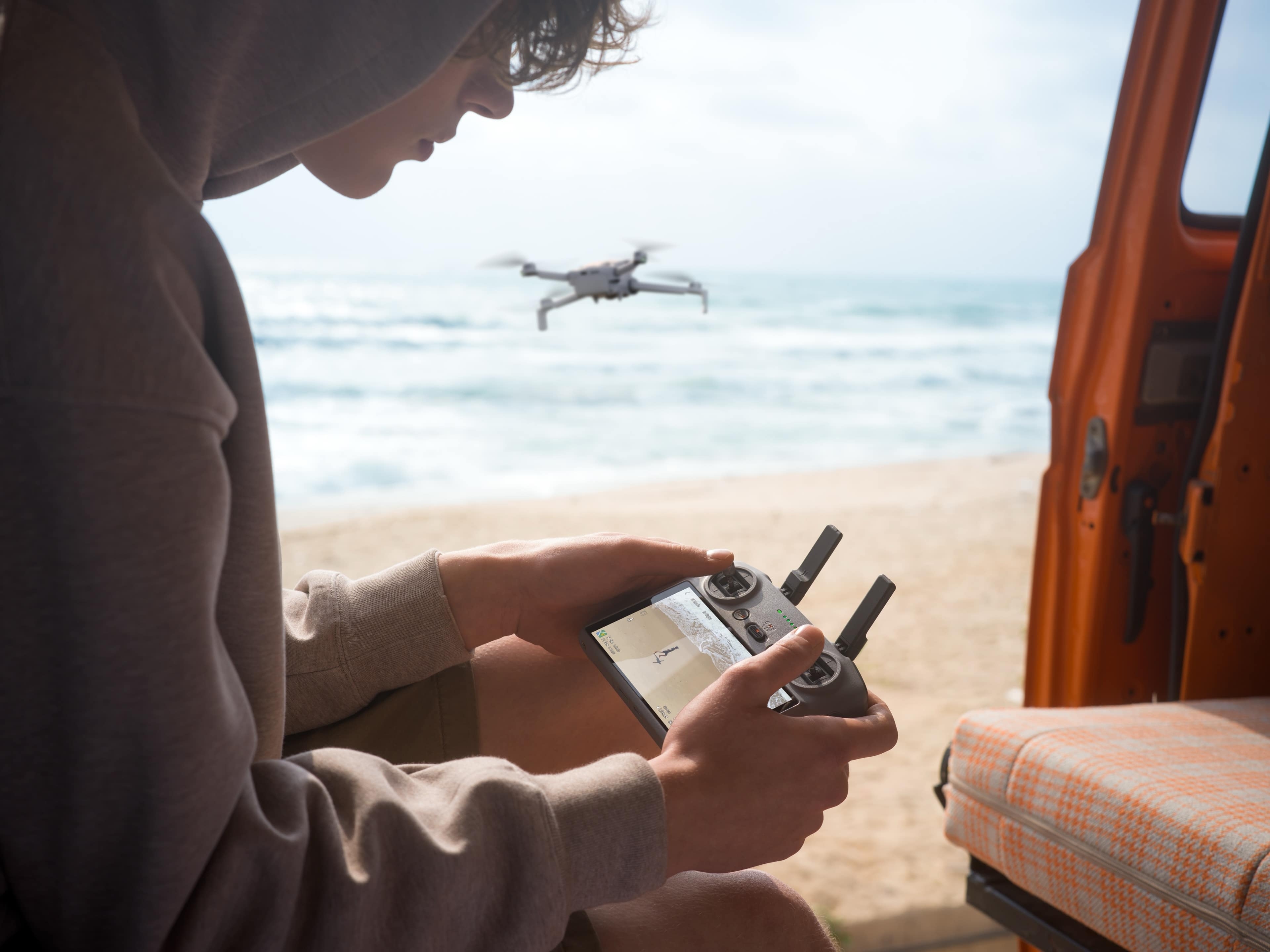 DJI Lito X1: Person steuert den Drohnenflug am Strand mit einem Handcontroller.