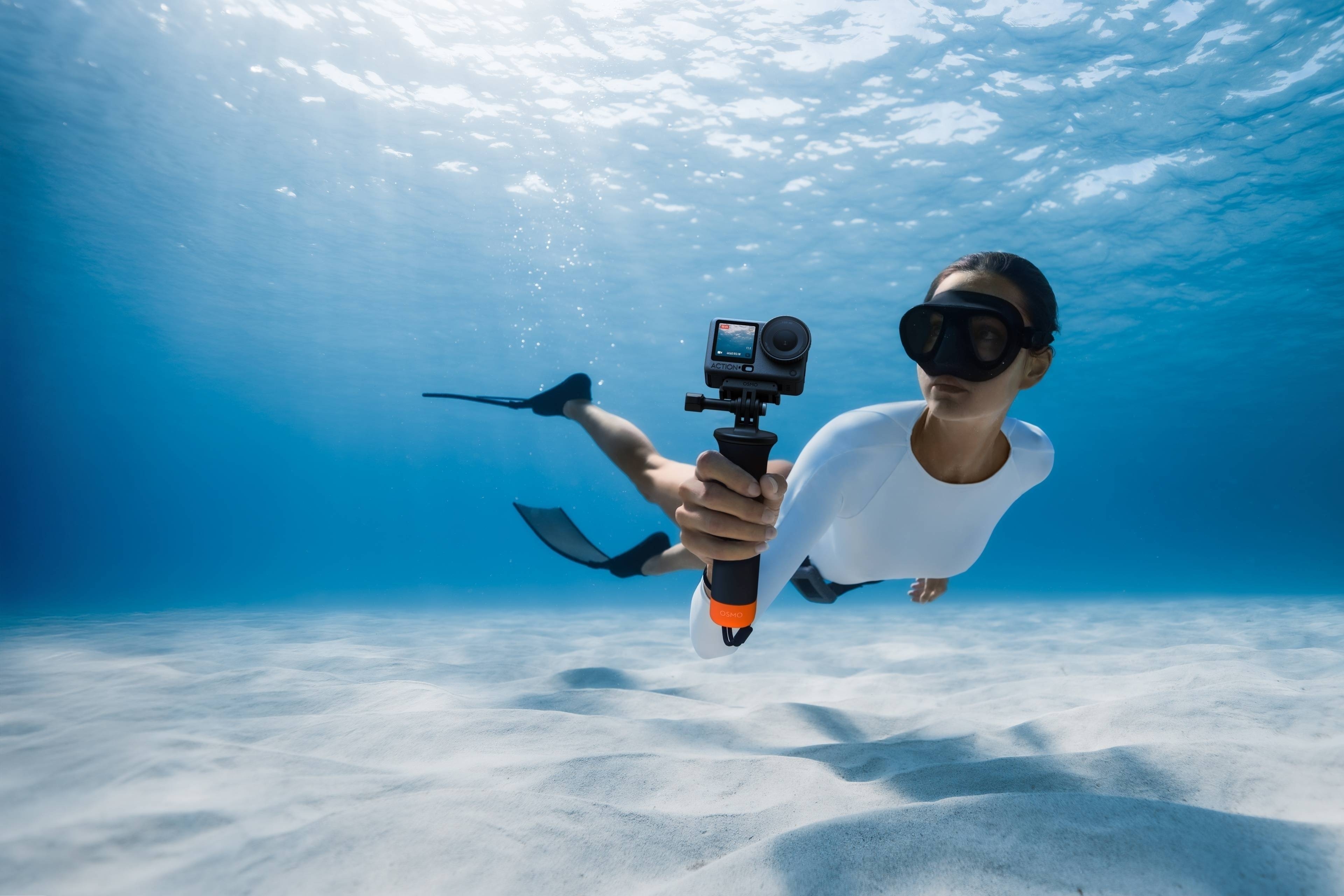 Unterwasseraufnahme einer Person mit Schnorchel, die die DJI Action 6 Kamera hält.