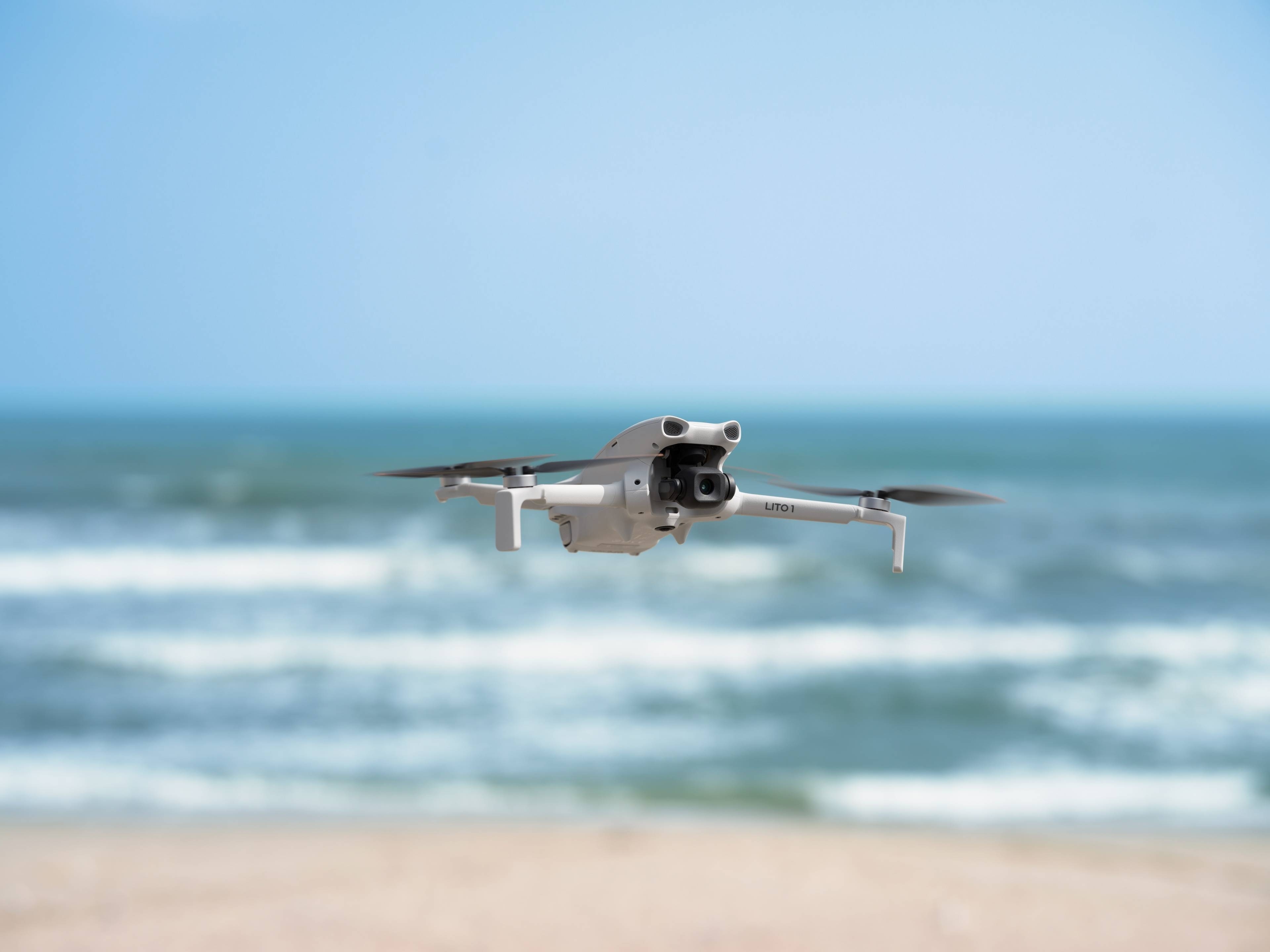 DJI Lito 1: Drohne in der Luft über dem Meer, mit weißen Wellen im Hintergrund.