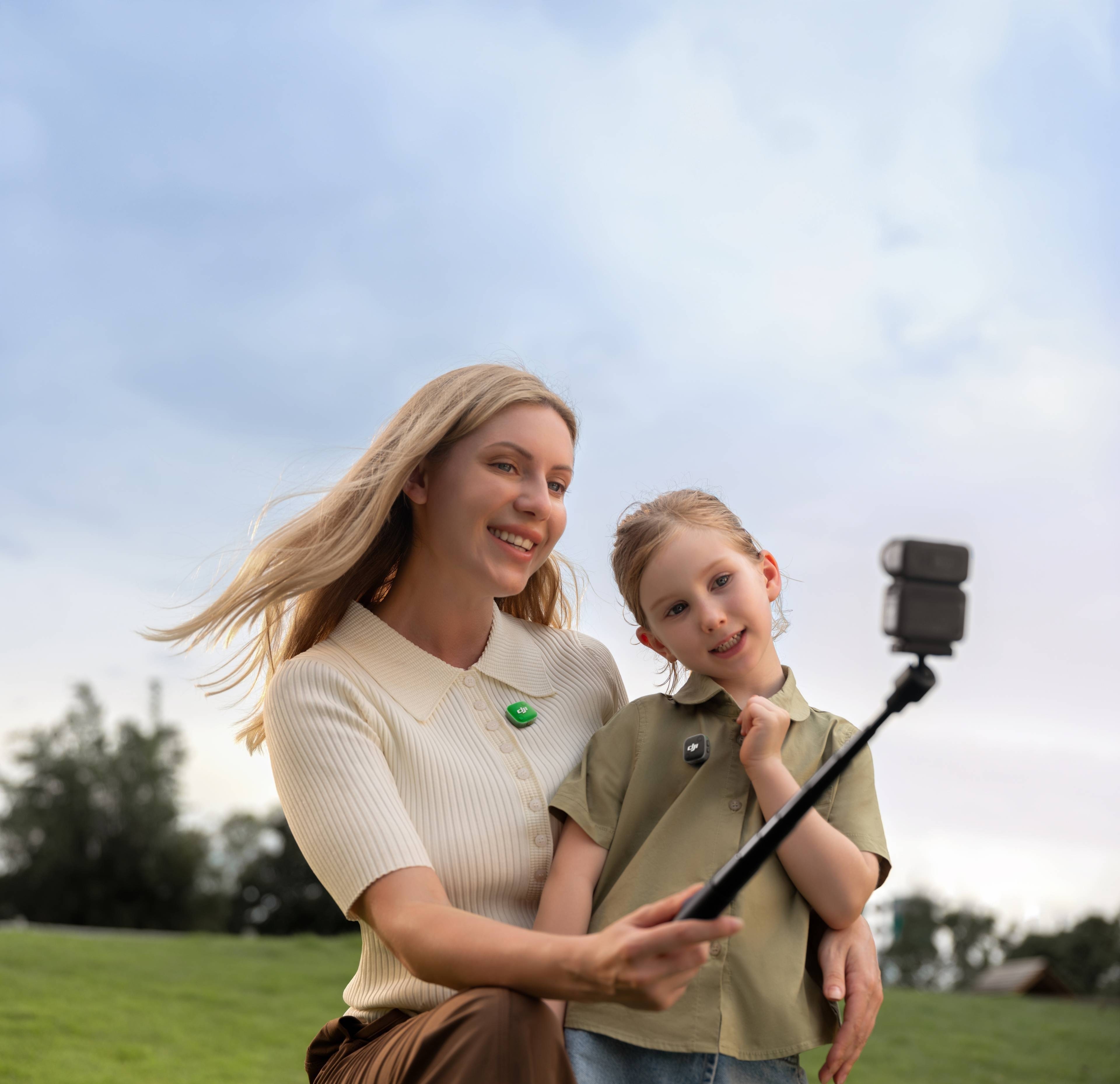 Mutter und Tochter mit DJI Mic Mini 2 (2 TX + 1 Mobile RX + Ladecase) beim Selfie im Freien.