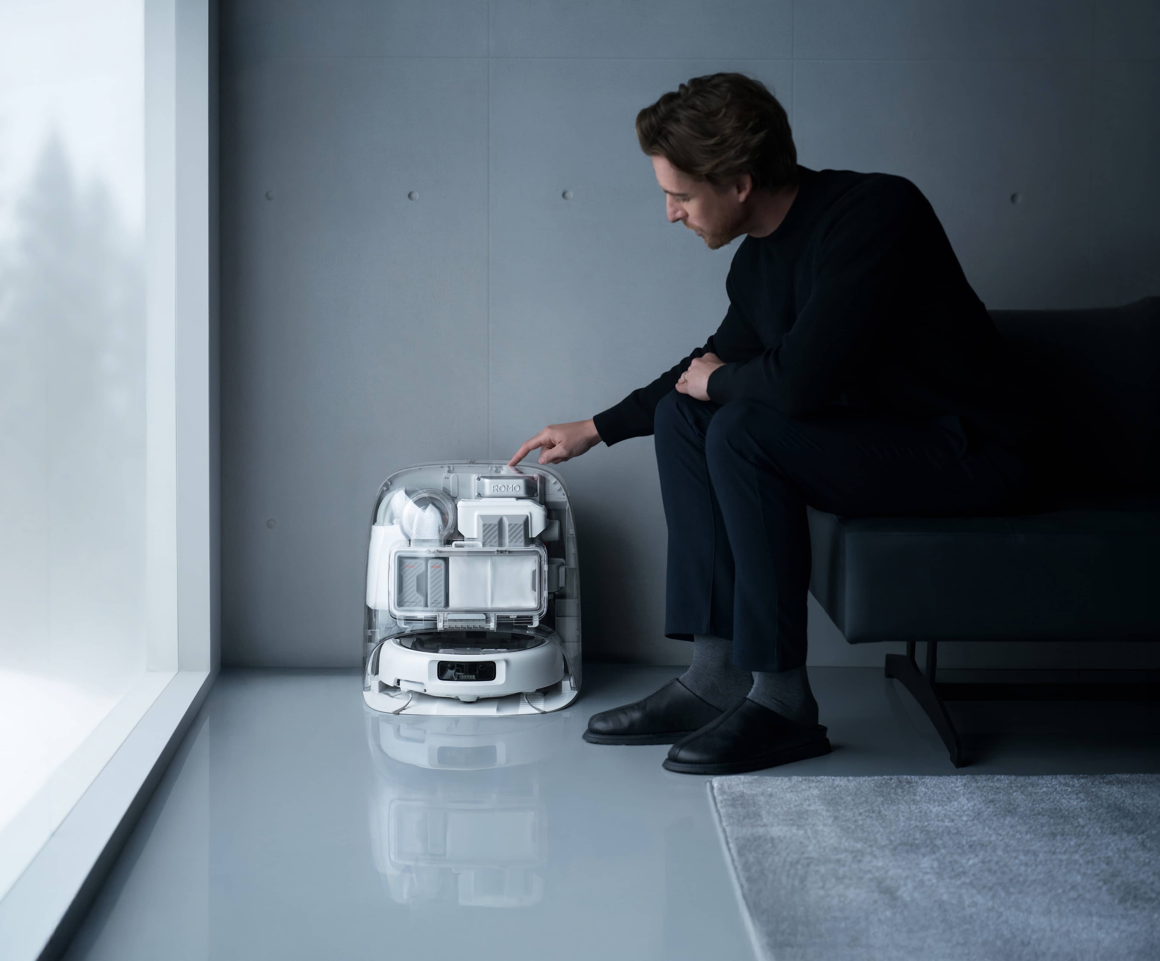 DJI ROMO P (Water Tank Version) in klarer Bauweise, Nutzer interagiert mit dem Gerät in modernem Raum.