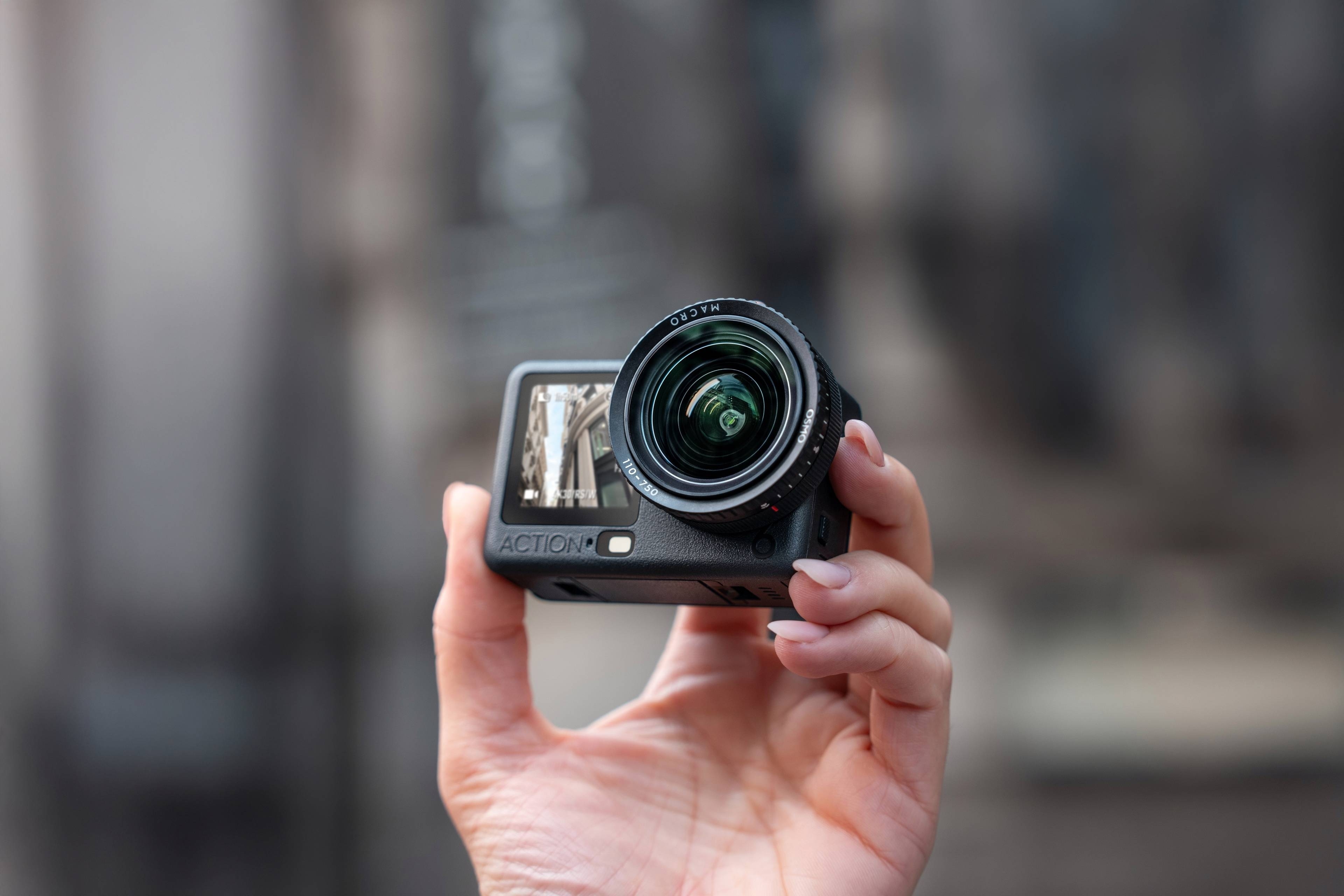 Hand mit der DJI Action 6 Kamera, ausgestattet mit Zoomobjektiv und kompaktem Design für Actionaufnahmen.