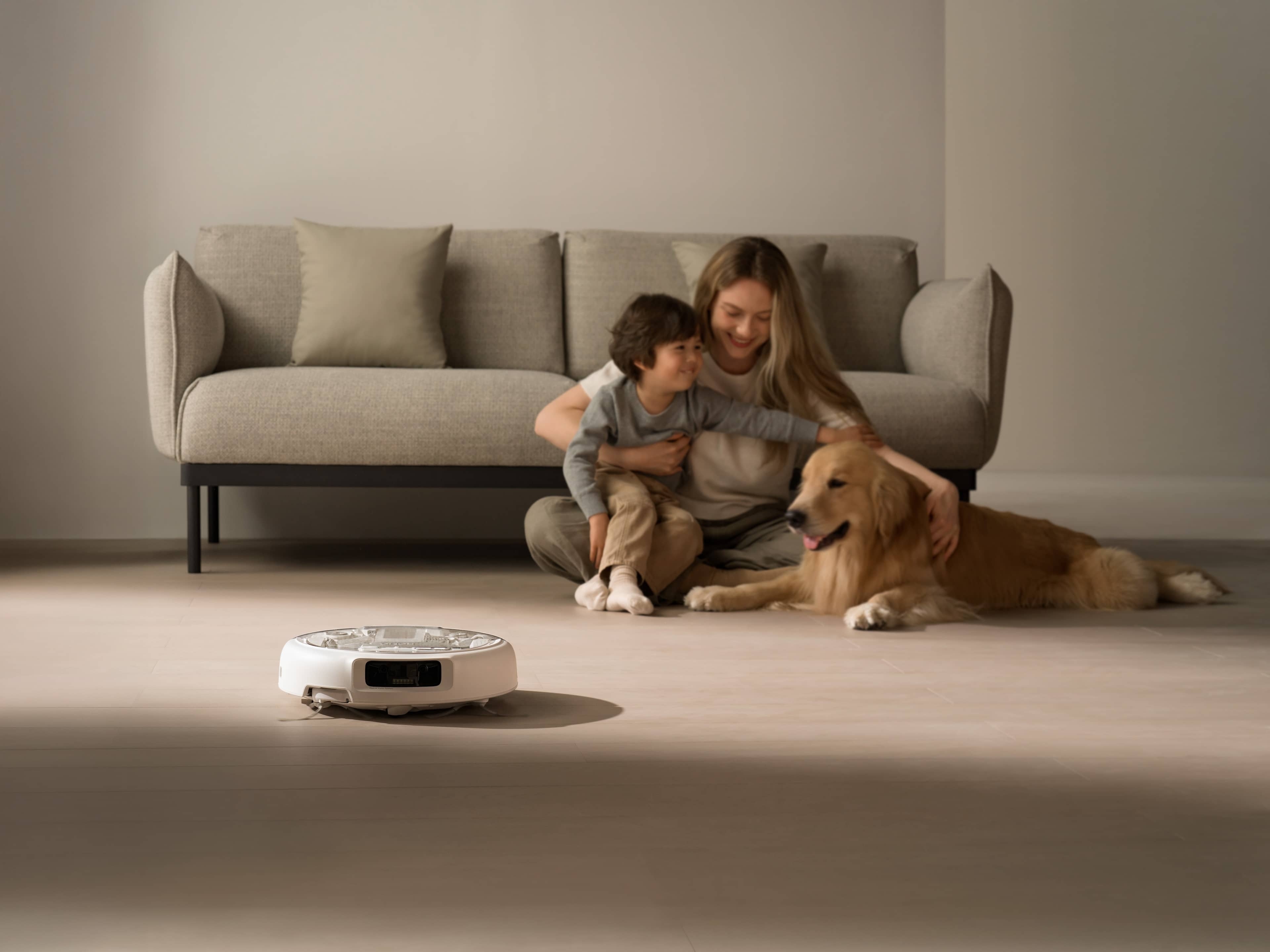 DJI ROMO A (Water Tank Version) mit Familie und Hund auf dem Boden im Wohnzimmer.